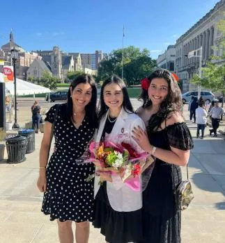 Maria, wearing her white coat, with her mother and sister