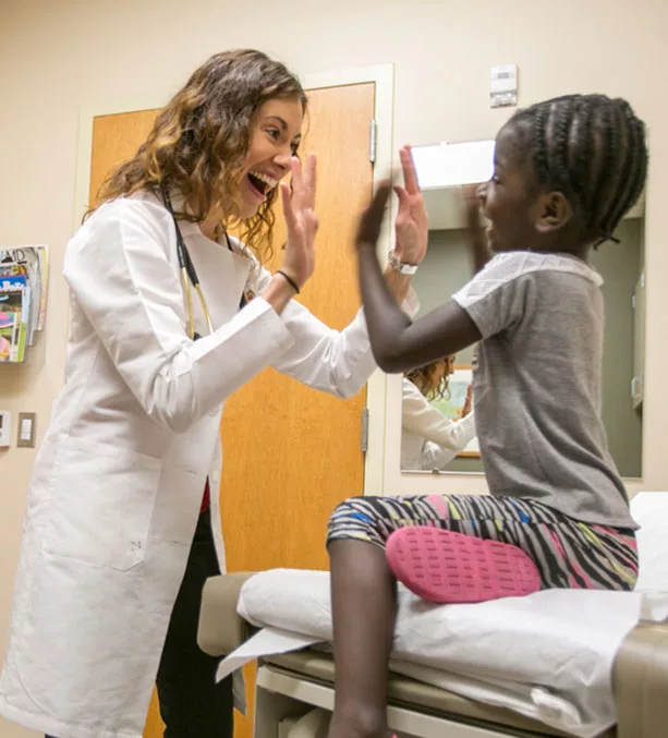 Jacqueline Gerhart smiles and gives her child patient high fives