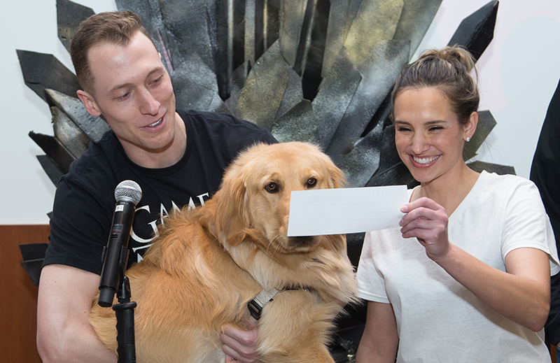 A man, woman and golden retriever dog all look at a piece of paper from the Match Day event in 2018