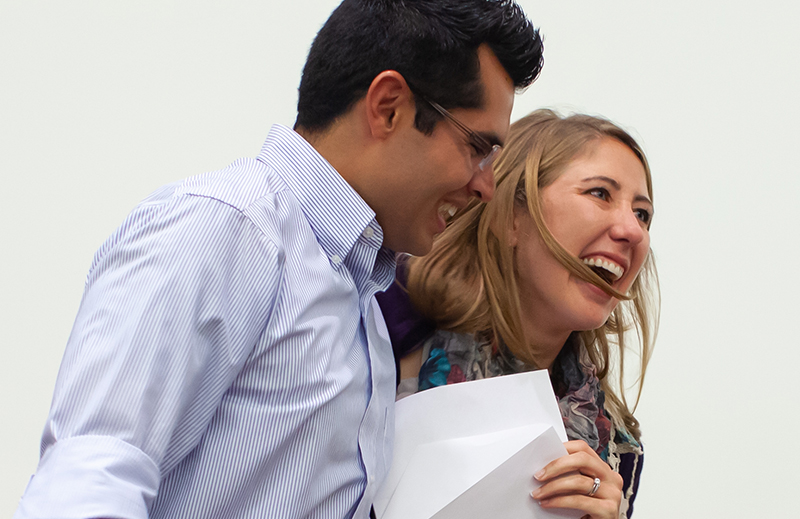 A man and a woman hold a piece of paper at a Match Day event while smiling