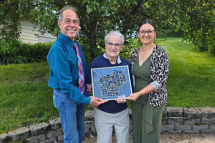 Jeffrey Polzin and Eugene Krohn present Michelle Clark-Forsting with the Max Fox award: a stained glass window depicting the state of Wisconsin