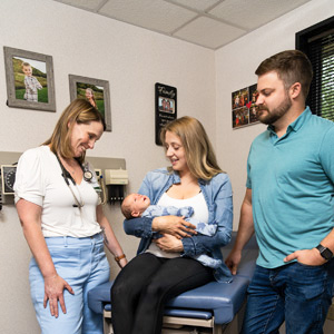 Elroy Jenna at Elroy Family Medical Center with photos of her family in the background admires a baby she delivered and meets with the parents.