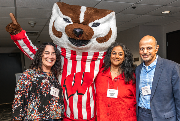 Homecoming attendees smile together with Bucky Badger