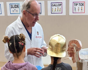 A doctor explains a model to two children