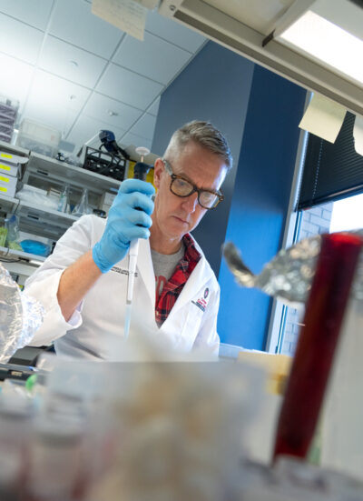 Denis Lee holding a pipette.