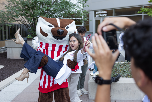 Bucky Badger holds a woman at a cookout event