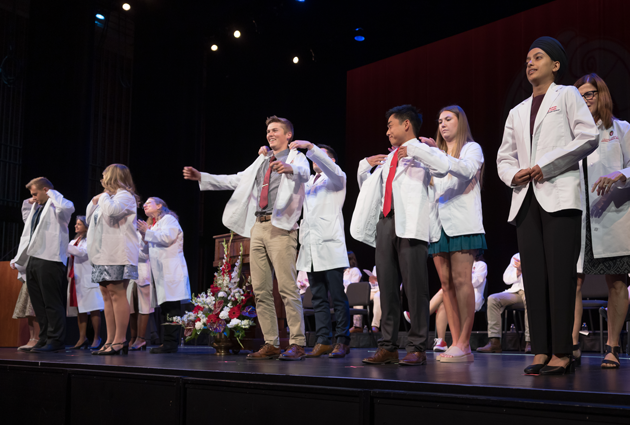 A group of people on stage for a white coat ceremony