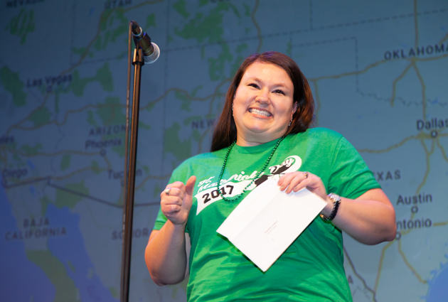 A woman in a green shirt appears excited while holding an envelope on Match Day