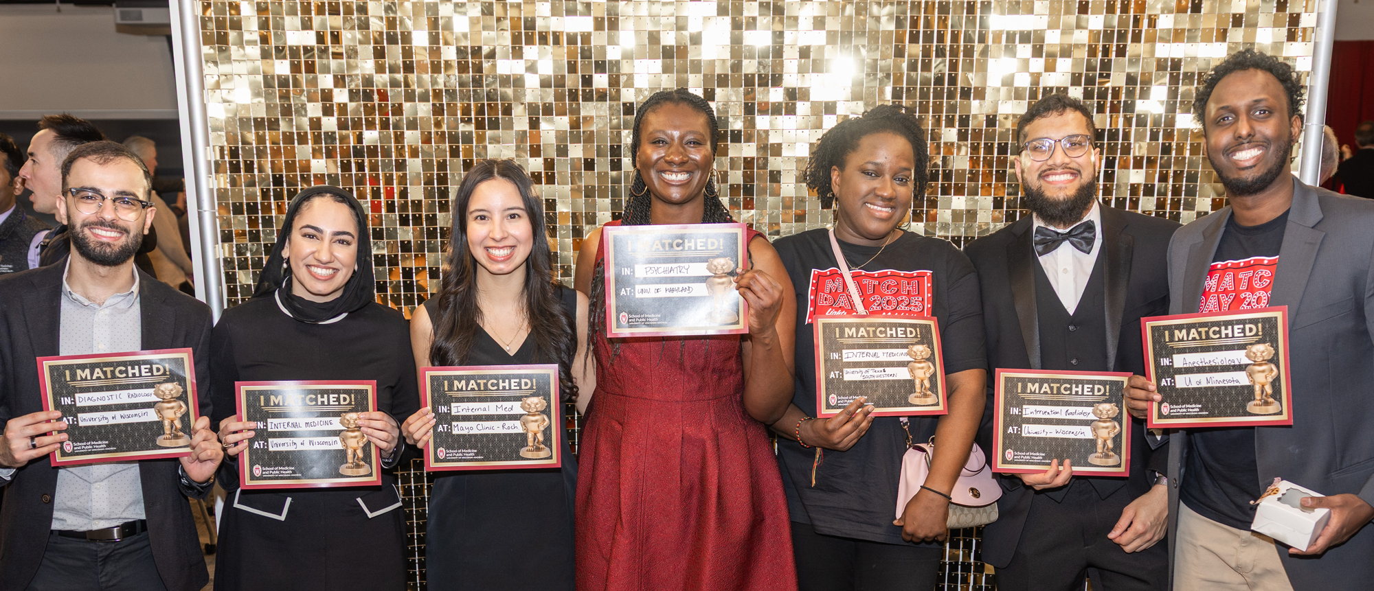 A group of seven people pose with signs during the Match Day 2025 event