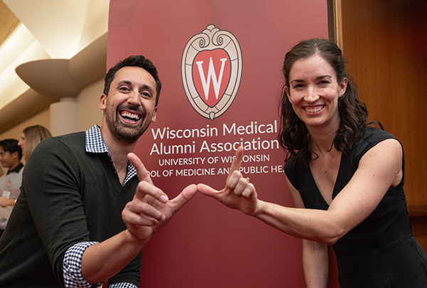 Two Homecoming attendees displaying a W with their hands