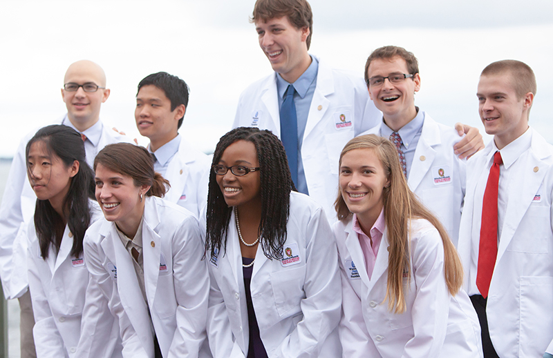 A group of nine people wearing white medical coats