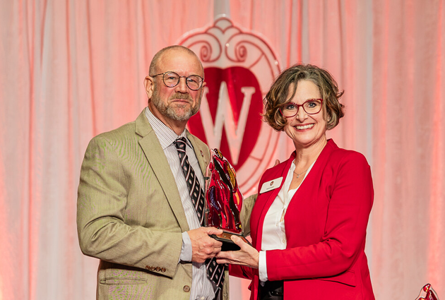 Two people stand with an award