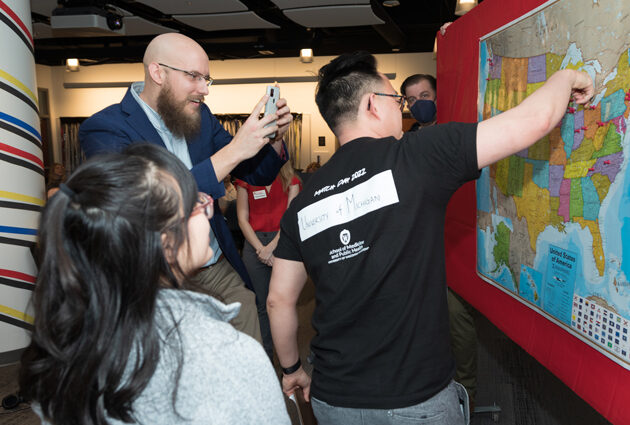 A man in a black shirt points to a map while onlookers observe during the 2022 Match Day event