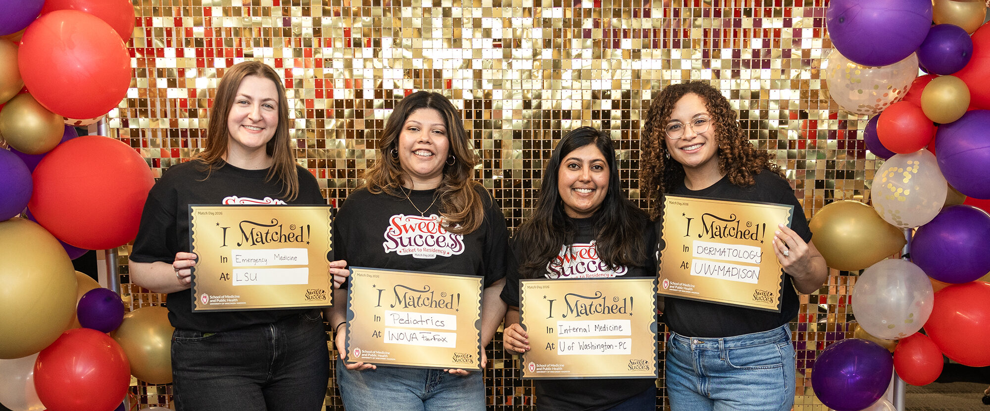 Four students smile on Match Day 2026 with gold signs