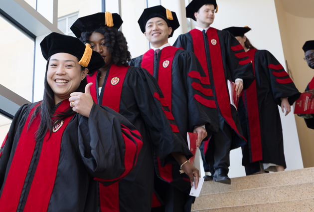 A group of people stand on the stairs in their graduation caps and gowns