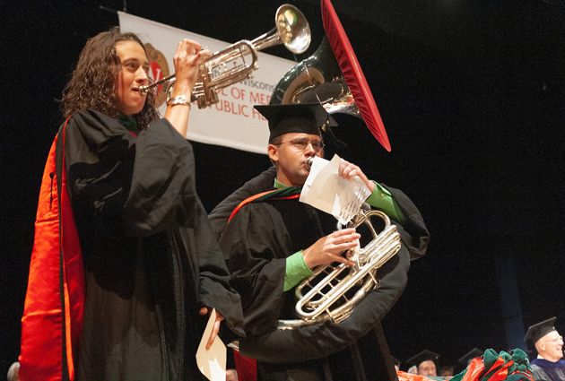 Two people play brass instruments at a graduation event