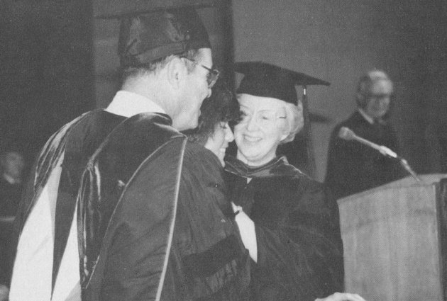 Two people shake hands at a graduation event