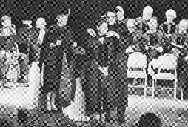 A woman stands on stage at a graduation event
