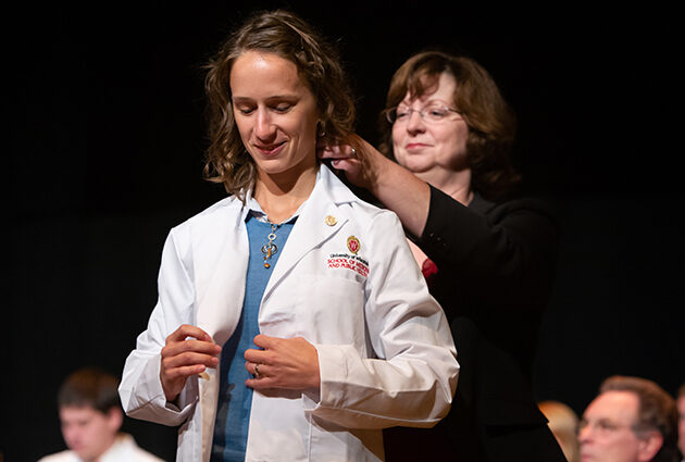 A person puts on a white medical coat