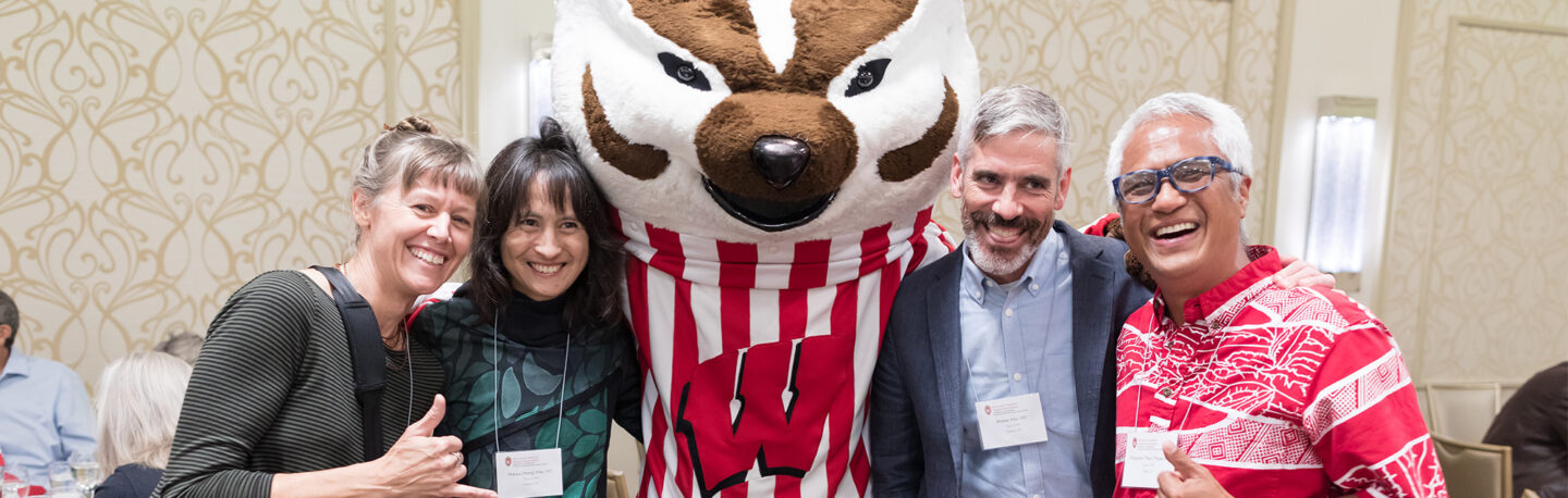 Homecoming attendees smile together with Bucky Badger