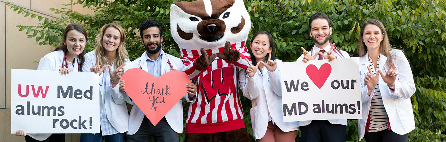 Medical students posing with Bucky and holding signs saying thank you to alumni