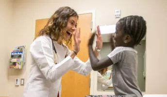 Smiling doctor high fives a young patient