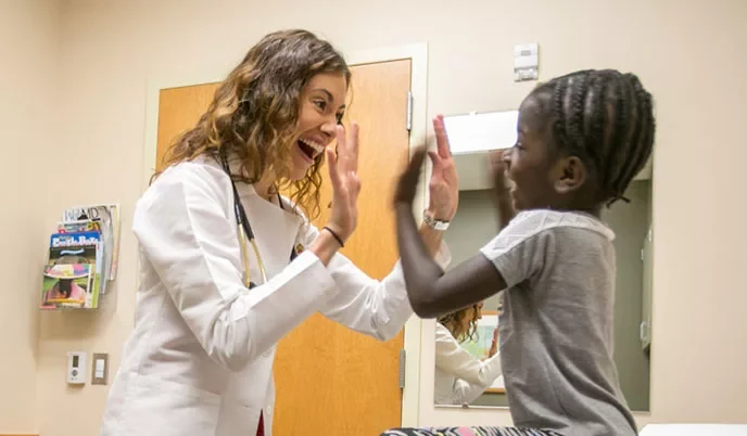 Smiling doctor high fives a young patient
