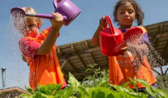 Kids using watering cans to water plants at Troy Kids' Garden