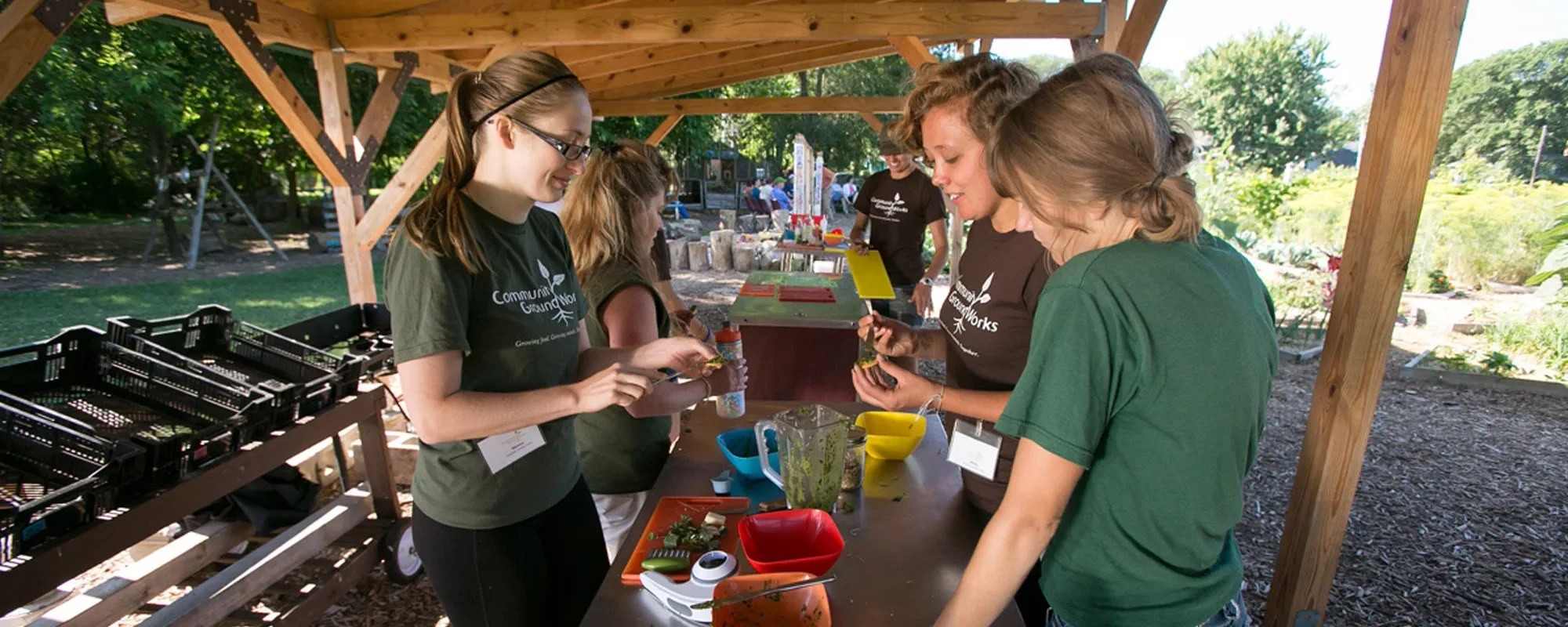 A group of educators use a blender on fresh ingredients at Troy Gardens
