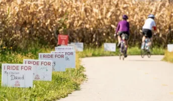 Signs along a bike path displaying the names of people the bikers ride on behalf of