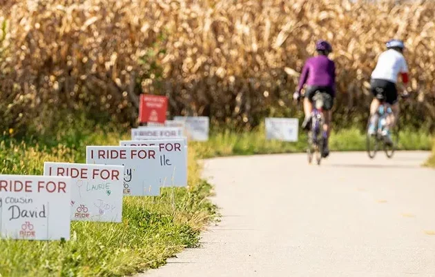 Signs along a bike path displaying the names of people the bikers ride on behalf of