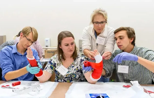 Students using great focus to practice applying a cast to a person's wrist and forearm