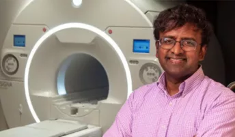 A researcher posing for a photo in front of an MRI machine
