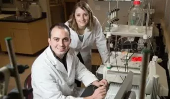 Two scientists in a lab posing for a photo