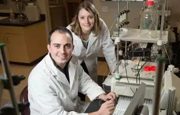 Two scientists in a lab posing for a photo