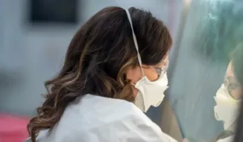 A virologist doing work in a lab with a mask and safety glasses