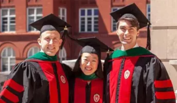 Three graduates smiling for the camera in their graduation attire