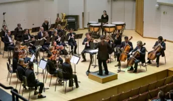 An orchestra playing on a stage with a conductor