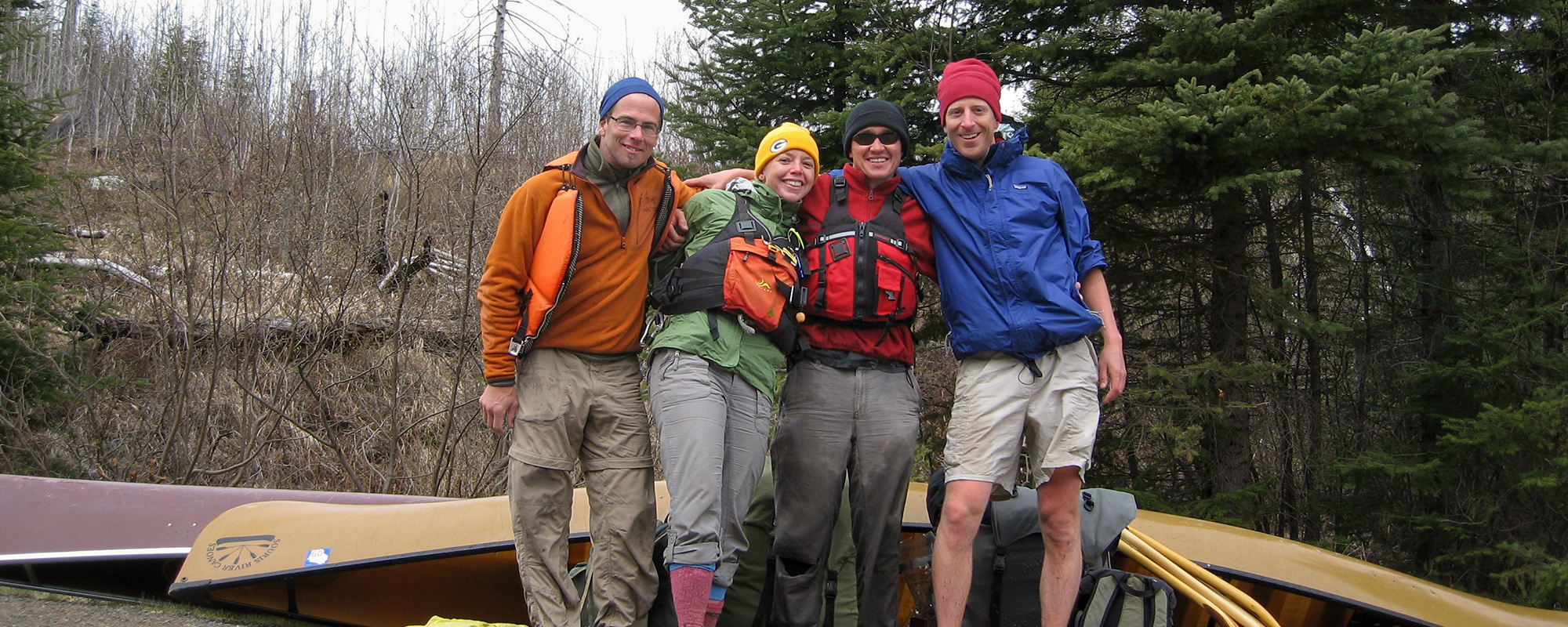 4 fields smiling in the woods in front of canoes (left to right: Laurence, Cramer, Hansen, Almasi)