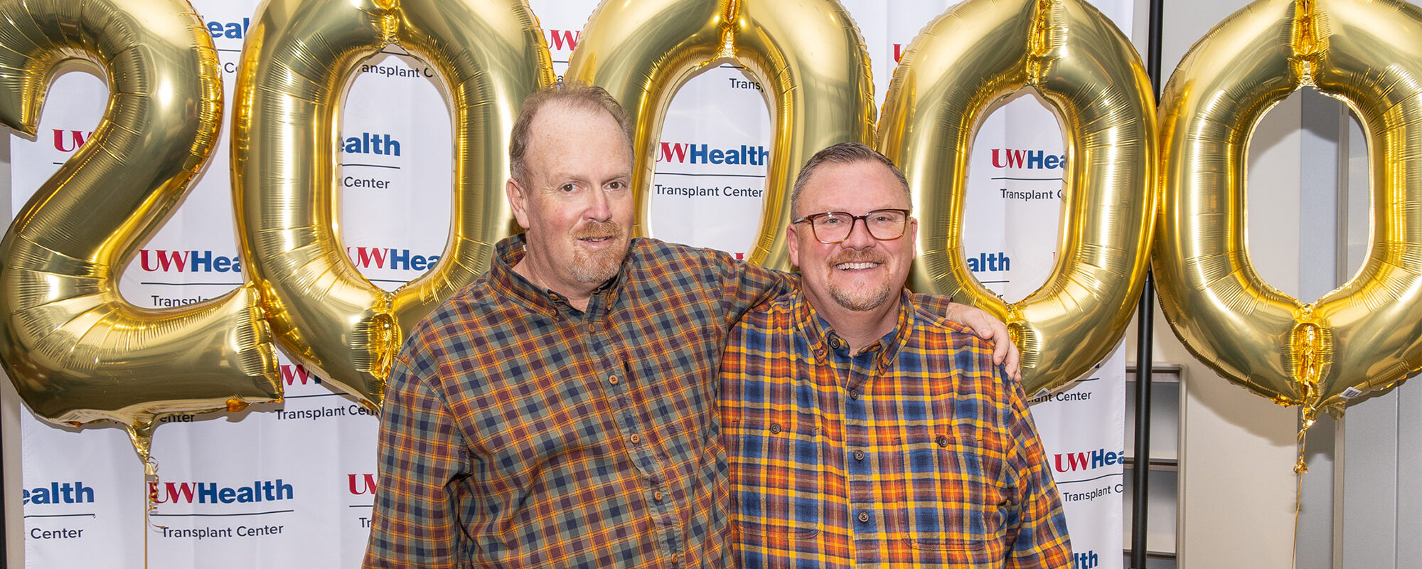 Gary Grosklaus and his brother pose in front of balloons celebrating the 20,000th organ transplant