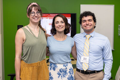 Two students and a faculty member smiling arm in arm