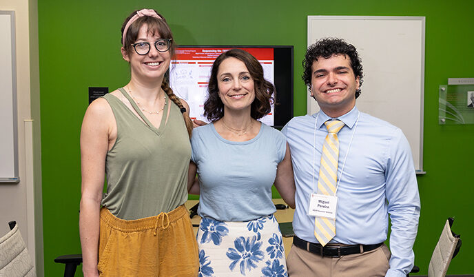 Two students and a faculty member smiling arm in arm