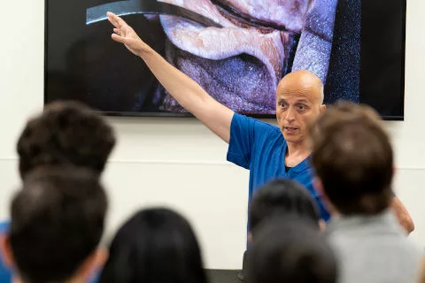 A professor lecturing in front of a TV screen