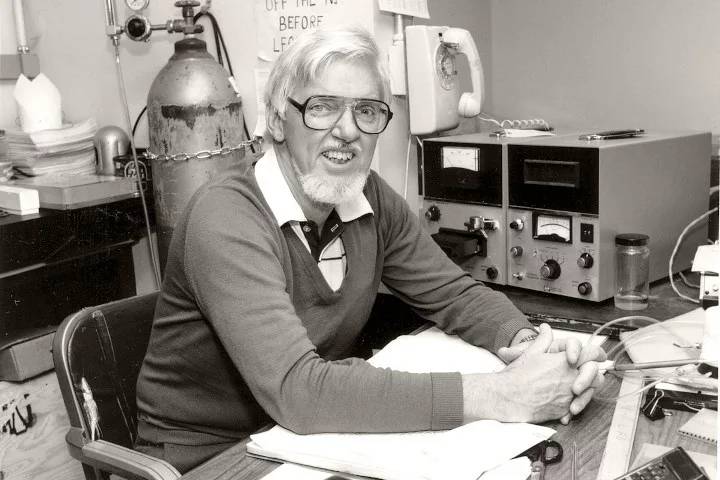 John Cameron sitting at a lab desk and smiling for the camera