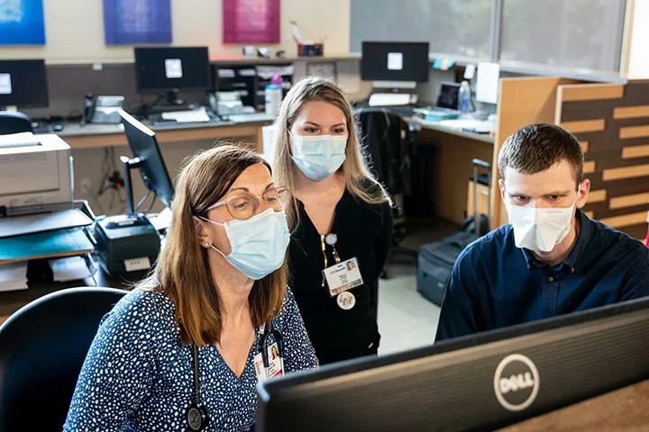 Masked medical professionals looking at a computer monitor