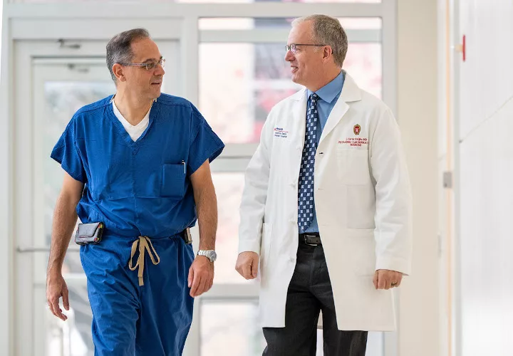 Two doctors talking as they walk down a hallway
