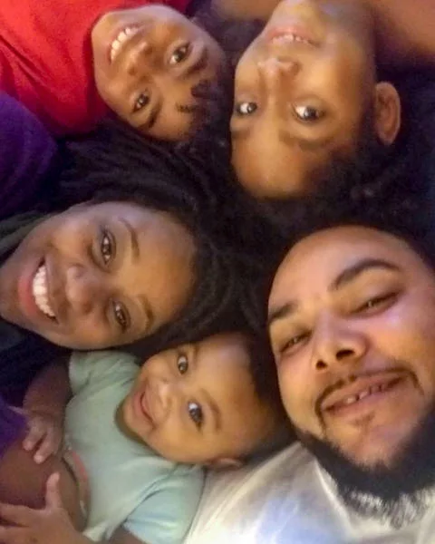 Five family members laying down with their heads together, smiling