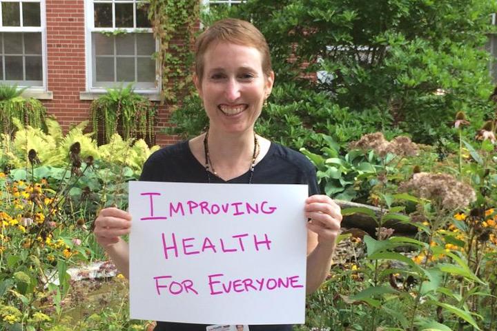 Beth Potter holding a sign that says 'improving health for everyone'