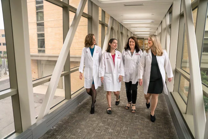 breast cancer researchers walking together down a hallway, on the move