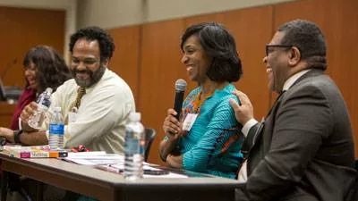 Three people having a laugh while leading a panel discussion